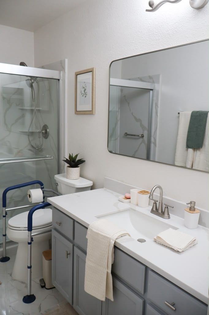 A bathroom at Cozy Care Homes with a walk-in shower, grab bars, and a support frame beside the toilet